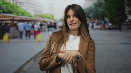 Fototapeta premium Hispanic woman gestures outdoors in bustling market street framed by urban city backdrop