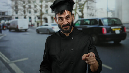 Hispanic chef in black uniform gestures energetically while standing on a busy street, engaging...