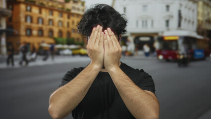 Young hispanic man with beard making funny faces on urban street with blurred buildings and traffic...