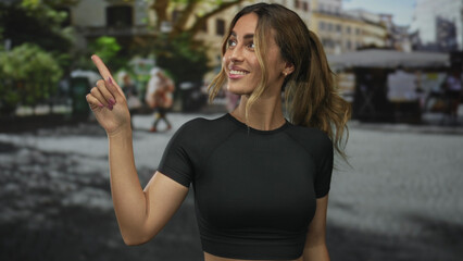 Fototapeta premium Woman pointing finger to side in plaza; friendly greeting.