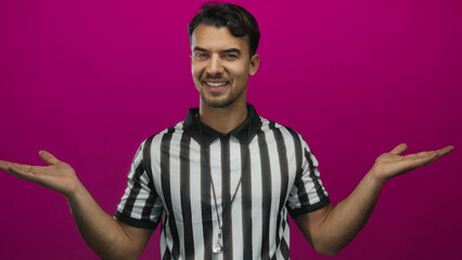Young hispanic referee man in a striped shirt extends hands sideways against an isolated vibrant...
