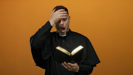 Young priest reading bible with surprise on bright orange backdrop, showcasing religious devotion...