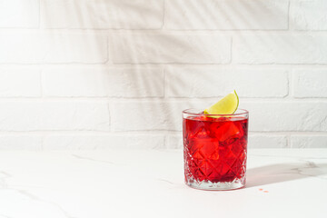 New Yorker red cocktail with whiskey, grenadine, bitter, lime and ice in glass.