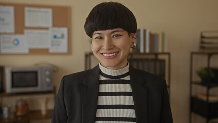 Young chinese woman in office gesturing silence with finger to lips wearing striped sweater and...
