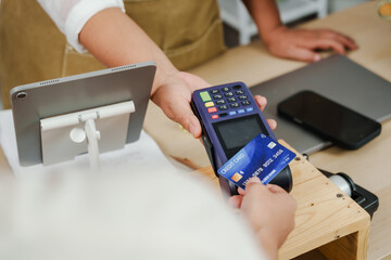 customer making payment with credit card using contactless method at wireless terminal in small...
