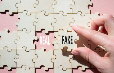 Real or Fake symbol. Concept word Real or Fake on wooden blocks. Businessman hand. Beautiful pink...