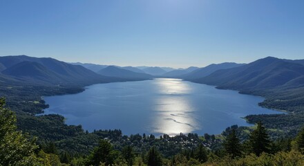 Aerial perspective of a large lake surrounded by mountains on a bright sunny day, with a clear blue sky