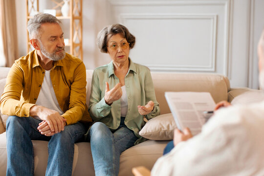 Marital therapy. Senior couple consulting with professional psychologist, sitting on sofa during psychotherapy session