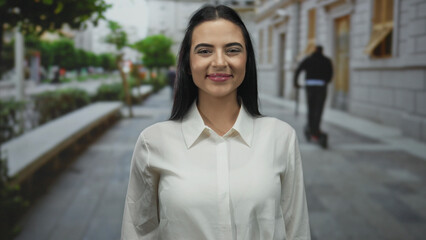 Fototapeta premium Woman in white shirt smiling on an urban street, showcasing lively hispanic culture in an outdoor city setting.