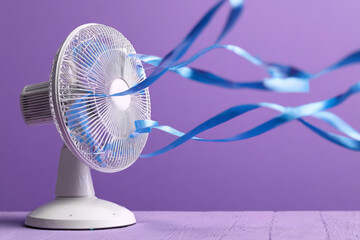 Tabletop Electric Fan with Flowing Ribbons Against a Violet Background
