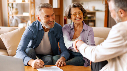 Happy senior couple making financial insurance estate deal, satisfied customers shaking hands with...