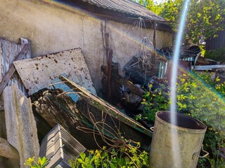 A pile of junk is in front of a house. The pile includes a broken piece of wood, a rusty metal...