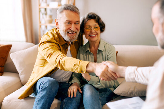 Successful deal. Happy senior spouses shaking hands with real estate agent, accepting his offer