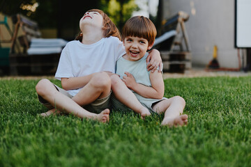 Fototapeta premium Happy children playing together on green grass, enjoying their time outdoors. The playful atmosphere captures childhood joy and friendship in a sunny setting.