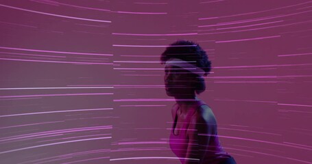 Female athlete picking up tennis ball and racket in studio, executing serve amid neon light streaks - Powered by Adobe