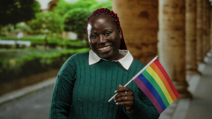 Woman holding rainbow flag on city street celebrating lgbt pride with joyful expression against...