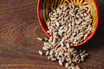 Raw sunflower seeds in ceramic bowl. Healthy food ingredient on wooden rustic table. Natural snack full of nutrients. Organic diet supplement. Vegetarian protein source. Decorative kitchen background.