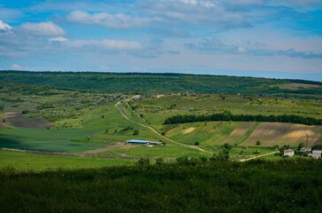 A large, open field with a blue barn in the middle. The sky is clear and blue, and the sun is...