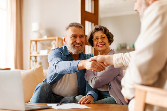 Satisfied senior spouses making sale purchase deal, handshaking with real estate agent agreeing to buy new house at meeting