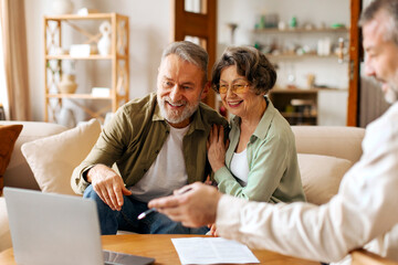 Senior couple having meeting with designer or broker looking at laptop and discussing choices....