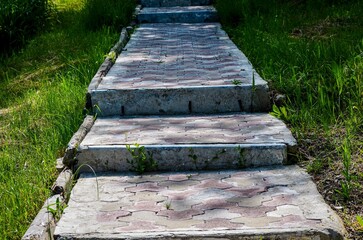 A concrete walkway with steps leading up to it. The steps are made of concrete and are covered in...