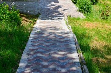 A brick walkway with a shadow cast on it. The shadow is on the ground and the walkway is made of...