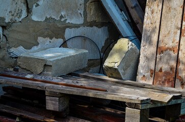 A pile of wood and bricks with a brick on top of a wooden pallet. The pallet is on the ground and the bricks are on top of it