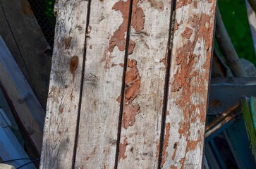 A wooden plank with brown paint on it. The paint appears to be chipping off, giving the wood a worn...