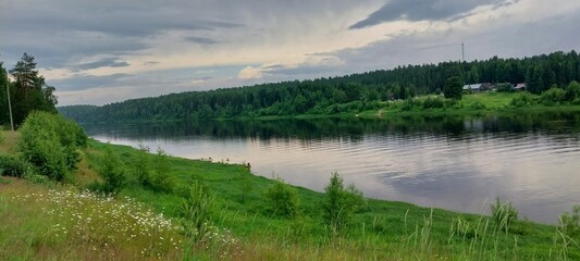 Serene River Landscape: Calm Waters and Lush Green Banks Under a Dramatic Sky for Nature-Inspired Design