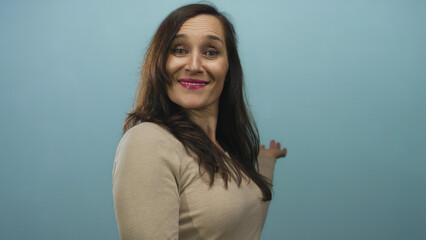 Young hispanic woman extends arms presenting against blue studio wall; welcome invitation...