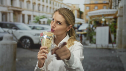 Young woman holding canadian dollars on a city street, showcasing money outdoors with a confident...