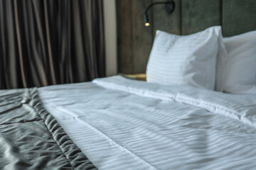 Close-up of neatly made hotel bed with white pillows and blanket, soft headboard and reading light....