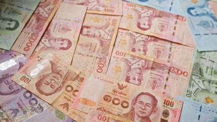 Thai banknotes scattered, showcasing various denominations of baht currency from thailand with no people visible.