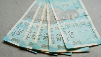 Indian fifty rupee banknotes spread on a concrete surface depicting currency from india.