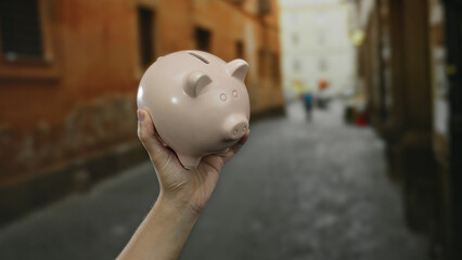 Male hand holding piggy bank in urban street setting highlighting savings and finance in a vibrant...