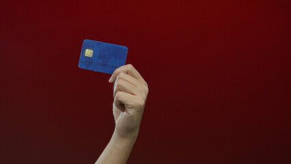 Man holding credit card against red background showcasing isolated financial concept with caucasian...