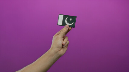 Man hand holding pakistan flag embroidery on pink background representing national pride and...