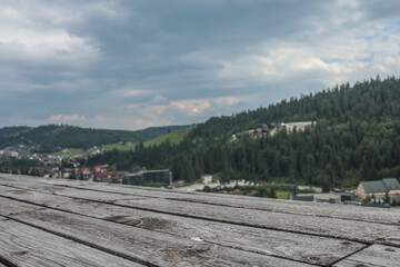 Wooden terrace with weathered planks overlooking a scenic mountain landscape and village under...
