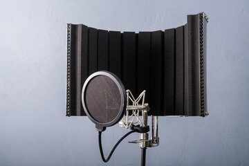 Studio microphone on a holder with a pop filter on a gray background