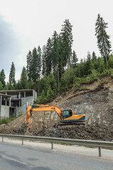 Excavator working at construction site near concrete building structure. Heavy machinery digging on...