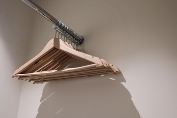 Set of empty wooden hangers neatly hanging on a metal rod in a modern closet. Minimalist and clean...