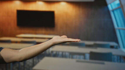 Man extending arm with palm open in an empty university classroom featuring modern design and...