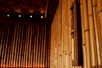 Closeup of bamboo sauna wall with wooden hourglass timer and soft warm lighting. Natural and...