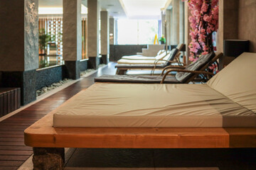 Luxury indoor spa area with modern wooden loungers, pool, stone elements, soft lighting and natural decor. Peaceful atmosphere for relaxation, wellness and rejuvenation