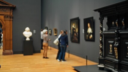 Woman viewing blurred paintings in a defocused museum gallery with wooden floors and statues,...
