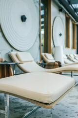 Close-up of modern spa lounge chair in bright relaxation area with minimalist decor, large windows, and natural light. Stylish wellness interior for rest and leisure