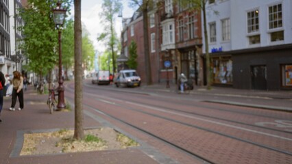 European city street with blurred pedestrians and vehicles under a defocused background of trees...