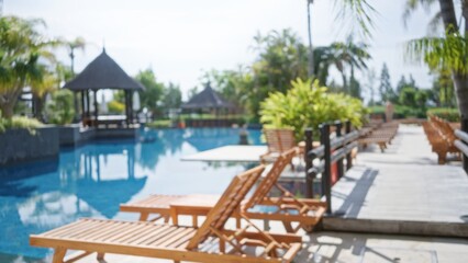 Blurred tropical resort scene with defocused sun loungers and vibrant foliage by a luxury poolside...