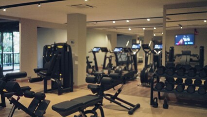 Blurred gym showcasing exercise equipment like treadmills and dumbbells, with a spacious indoor...