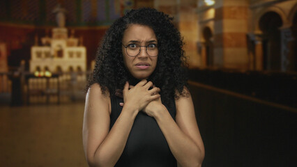 Young hispanic woman wearing round glasses and holding her throat with both hands inside a...